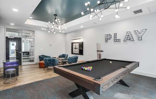a game room with a pool table and a play area with chairs