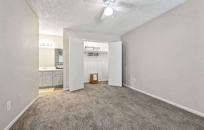 A room with a carpeted floor and a white ceiling fan.