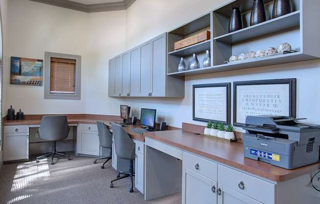 A well-lit office with a desk, chairs, and a printer.