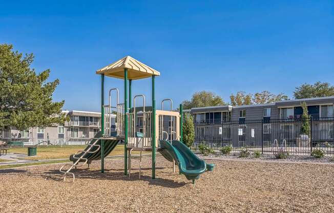 A playground with a green slide and a yellow canopy.
