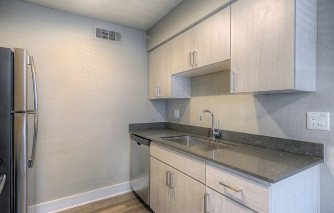 A kitchen with a refrigerator, sink, and cabinets.