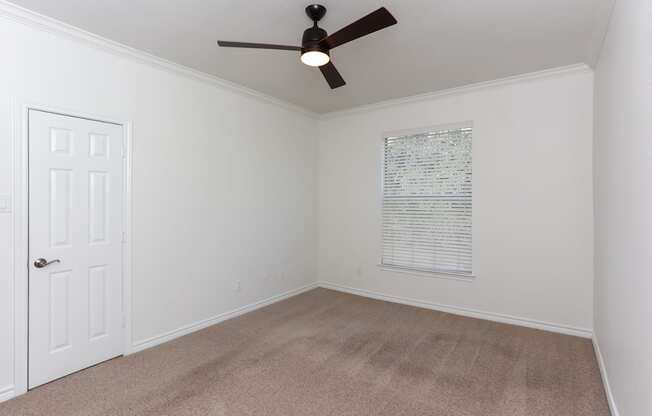 A room with a ceiling fan and a door.