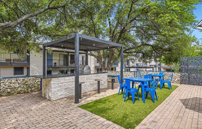 a patio with a blue table and chairs and a grill