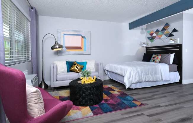 Fusion Las Vegas studio apartment sleeping and living area with large bed, geometric rug and decor, and black wicker coffee table.