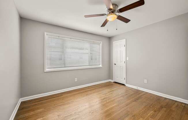 an empty living room with a ceiling fan and a window