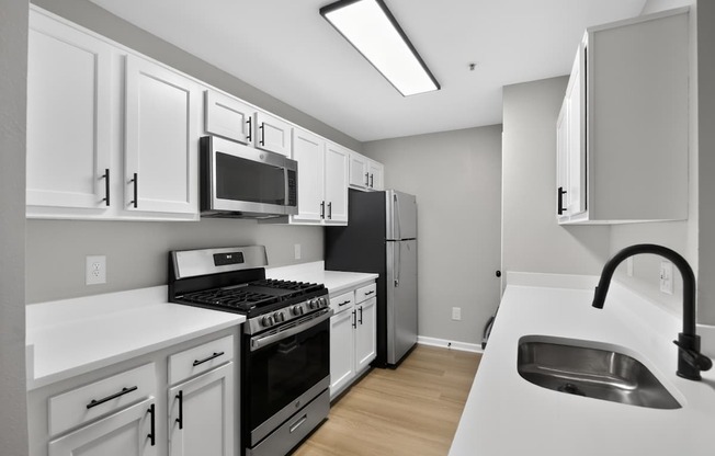 A kitchen with white cabinets and appliances.
