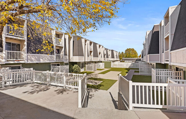 a row of apartments with white fences and lawns