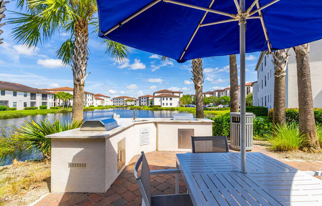 A blue umbrella is over a table and chairs.