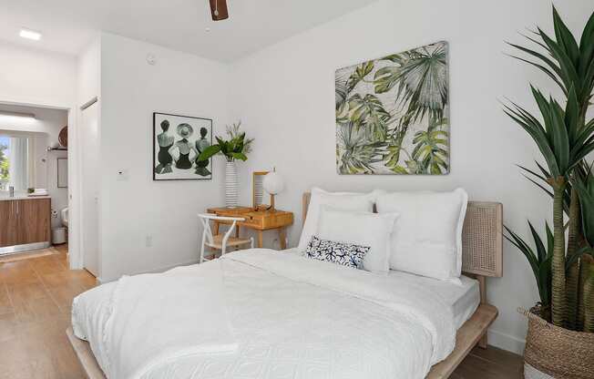 a bedroom with white walls and a white bed with white bedding