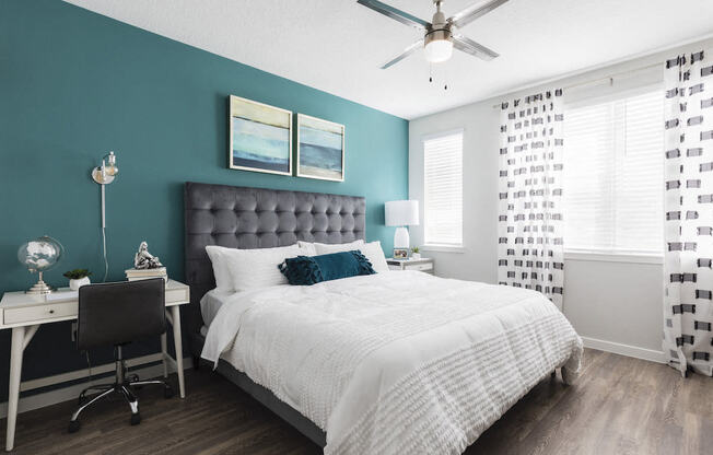 Bedroom with ceiling fan and large windows at Residences at The Green in Lakewood Ranch, FL