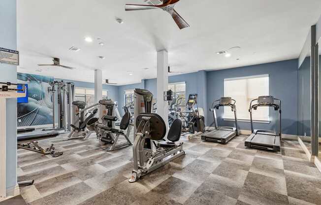 A spacious gym with a variety of equipment including treadmills, elliptical machines, and a rowing machine.