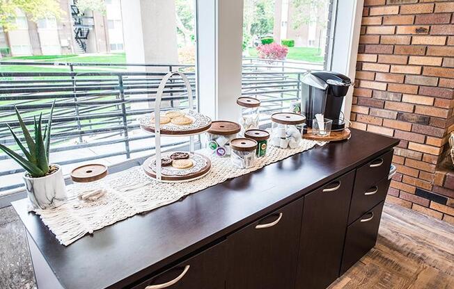 A coffee bar with a potted plant and a coffee maker on it.