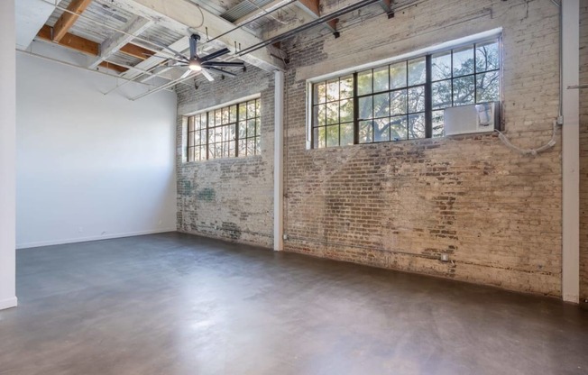 an empty room with a brick wall and a large window