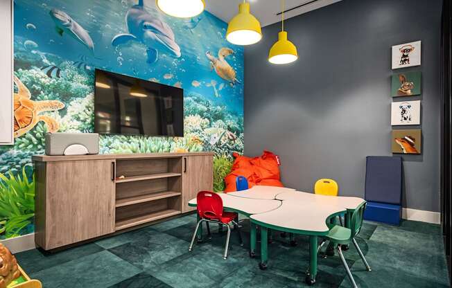 A room with a table, chairs and a mural of dolphins.