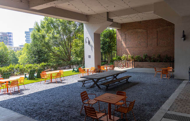 a patio with picnic tables and chairs in front of a brick wall