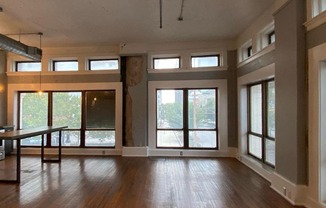 Large loft living area with high ceilings, hardwood floors, and big windows at Jemison Flats, Birmingham, AL