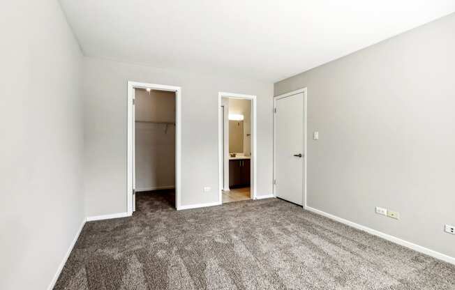 an empty room with carpet and doors to a bathroom