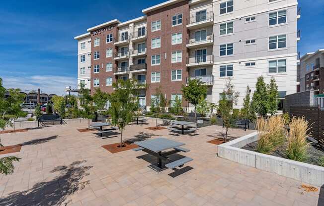 an outdoor patio with benches and trees in front of an apartment building