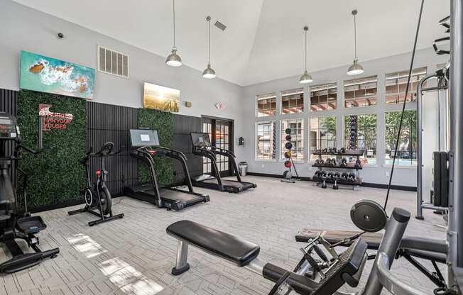 A gym with a variety of equipment including treadmills, weights, and exercise machines.