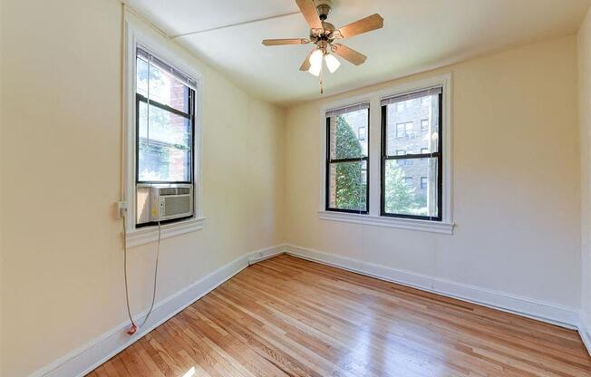 vacant bedroom with hardwood floorings, large windows and ceiling fan at the klingle apartments in washignton dc