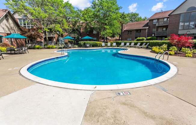 A round blue swimming pool surrounded by a concrete patio and a white border.