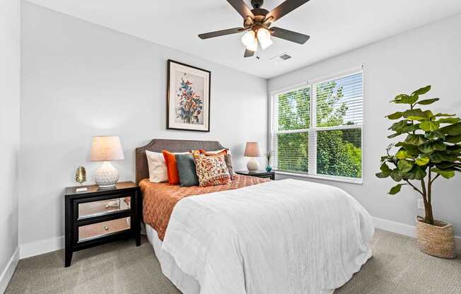 A bedroom with a bed, nightstand, and a ceiling fan.