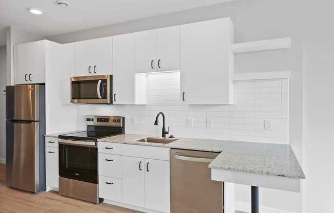 A kitchen with white cabinets and a granite counter.