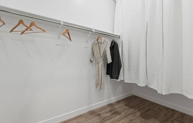 a white room with clothes hanging on a rack and a white curtain at Village of Chandler Apartments, Arizona