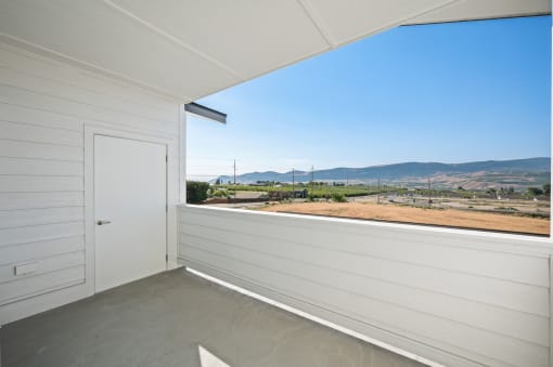 the view from the balcony of a white building with a door and a dirt field at Gateway Apartments, East Wenatchee , Washington