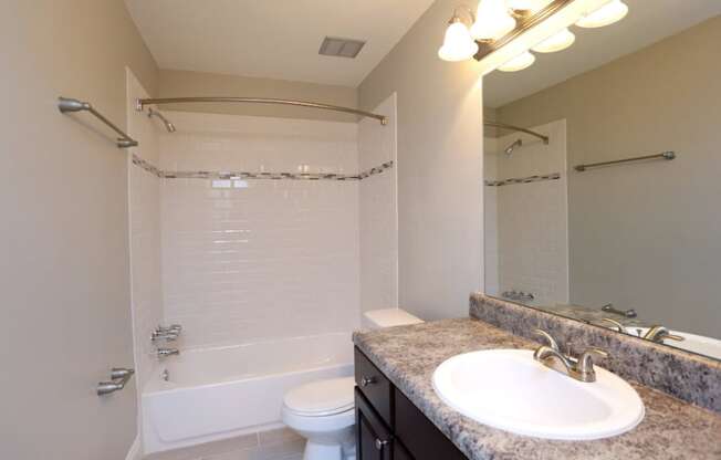 A bathroom with a white toilet, sink, and a shower with a glass door.