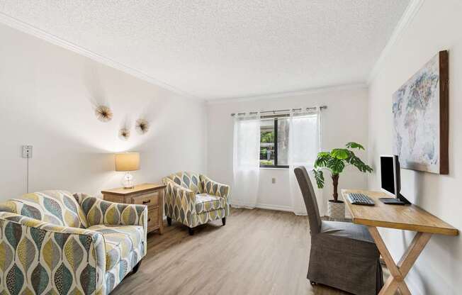 A living room with a couch, chair, and desk at Hampton Apartments, Clearwater