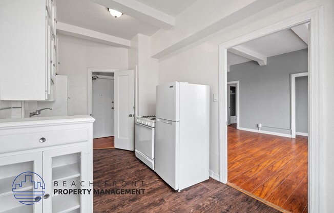 a kitchen with white cabinets and a refrigerator and a wood floor