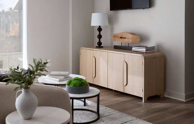 A white vase sits on a table next to a white chair and a green plant.