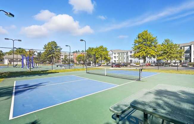 A tennis court with a green bench in the foreground.