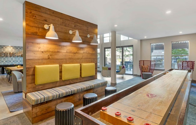 A shiny wooden air hockey table is in the middle of a room with a wooden wall and a bench at Glenwood at Grant Park, Georgia