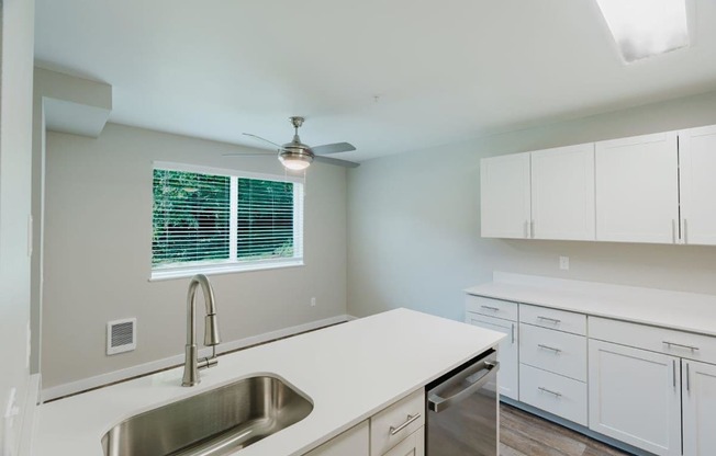 A kitchen with white cabinets and a stainless steel sink.