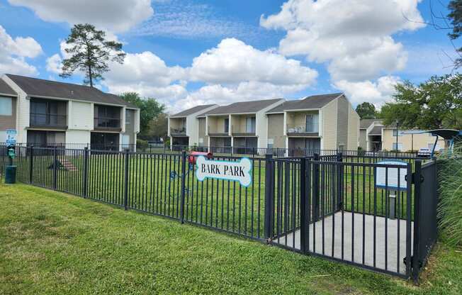 A row of apartment buildings with a sign that says Bark Park.