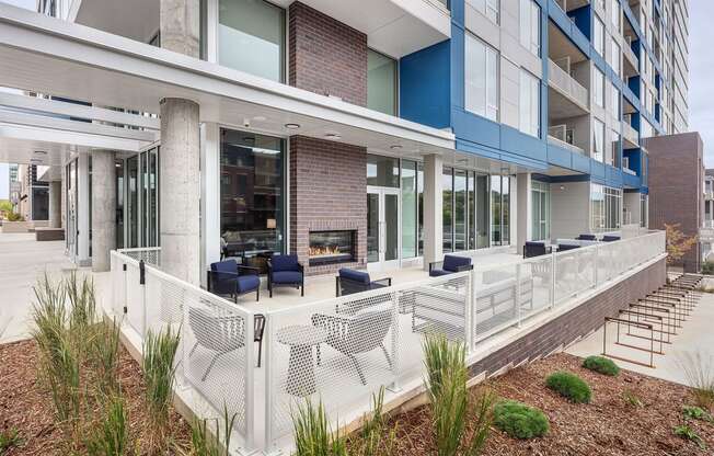 an outdoor patio with chairs and a fireplace at an apartment building