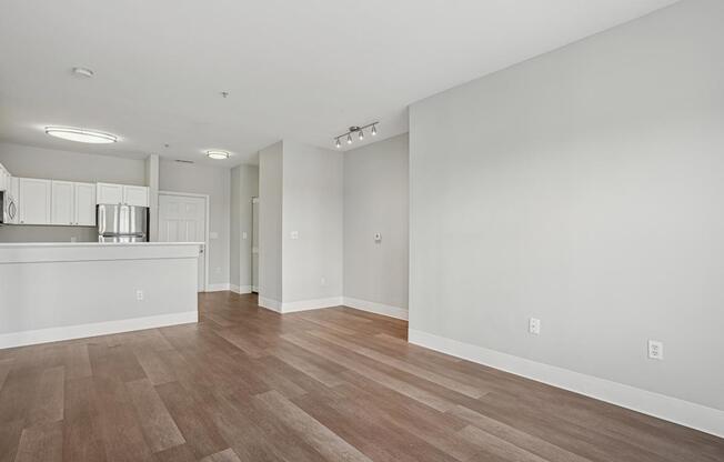 A spacious room with wooden flooring and white walls.