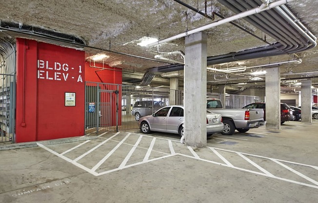 a parking garage with cars parked in front of a red wall at Mockingbird Flats, Dallas, TX