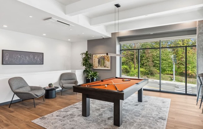 A room with a pool table and chairs.