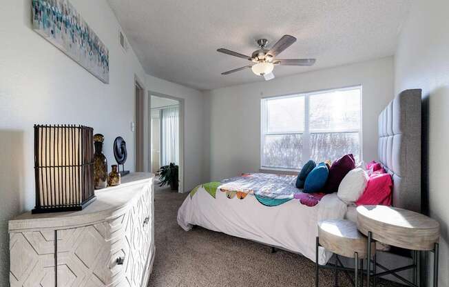The bedroom in the model unit at Skyler Ridge Apartments, featuring a bed and ceiling fan.