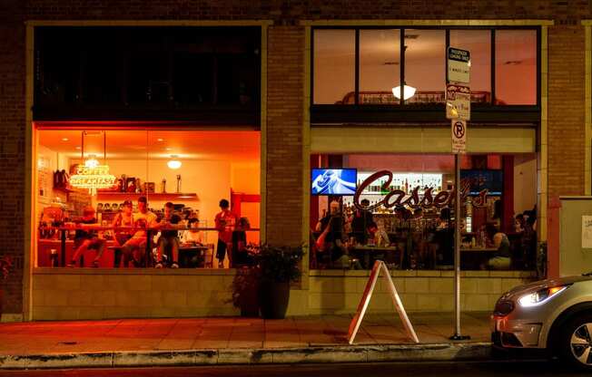 a restaurant with people sitting in the windows at night