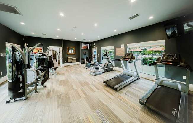 A gym with treadmilers, weights, and exercise equipment.