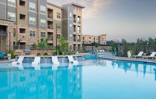 A large swimming pool in front of apartment buildings.