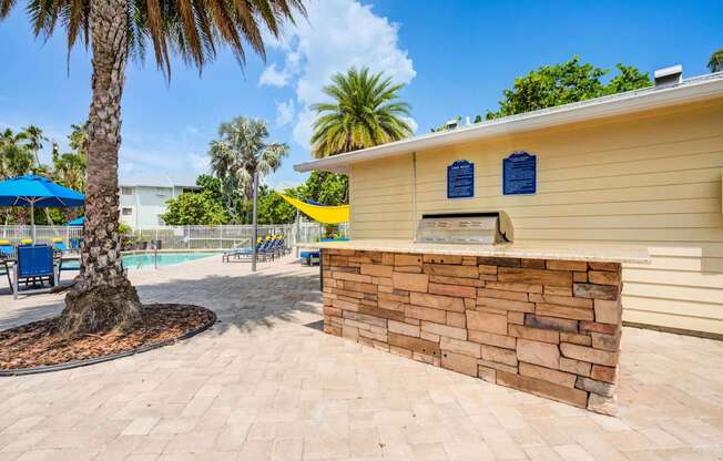 A yellow building with a stone wall and a palm tree in front.