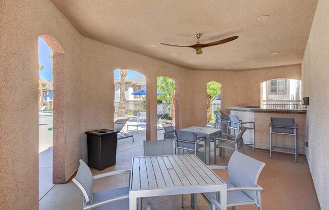 A patio with a table and chairs and a ceiling fan.