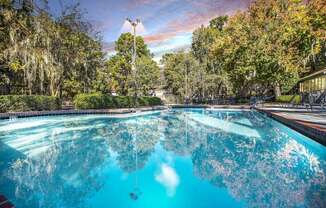 Greentree Apartments in Savannah, GA photo of a swimming pool with trees in the background and a cloudy sky