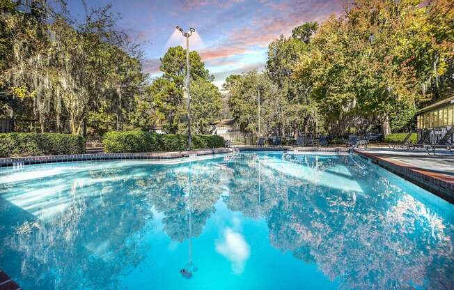 Greentree Apartments in Savannah, GA photo of a swimming pool with trees in the background and a cloudy sky