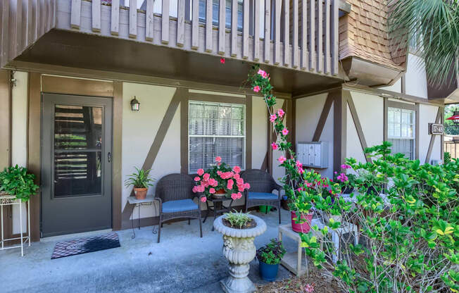 the front porch of a house with chairs and potted plants